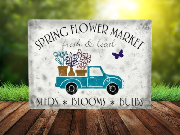 white distressed sawdust textured spring sign with teal truck carrying flowers