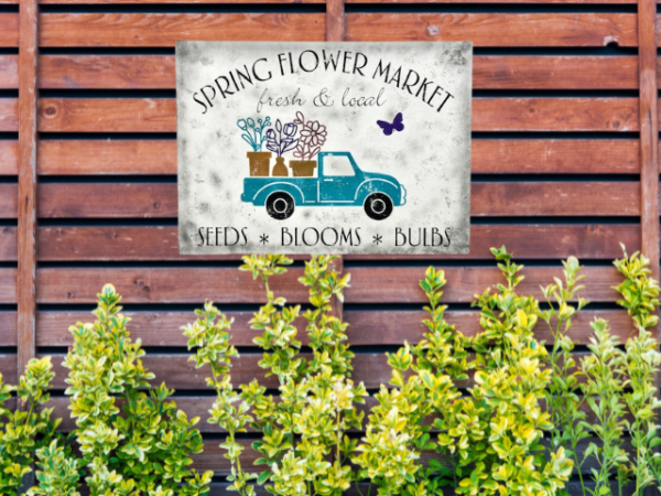 white distressed sawdust textured spring sign with teal truck carrying flowers