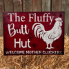 rustic sign with a red sawdust-textured background, featuring a chicken illustration and the text 'Fluffy Butt Hut - Welcome Mother Cluckers'