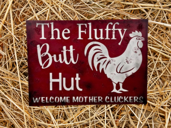 rustic sign with a red sawdust-textured background, featuring a chicken illustration and the text 'Fluffy Butt Hut - Welcome Mother Cluckers'