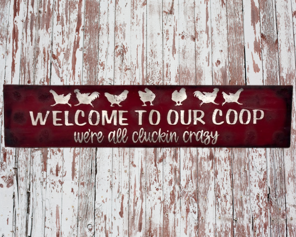 farmhouse chicken sign that has a deep red sawdust textured background with white chickens that reads Welcome to Our Coop, we're all cluckin crazy