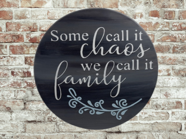 charming and elegant wood round sign that reads some call it chaos we call it family; colors are barnwood stain with ivory and light blue lettering