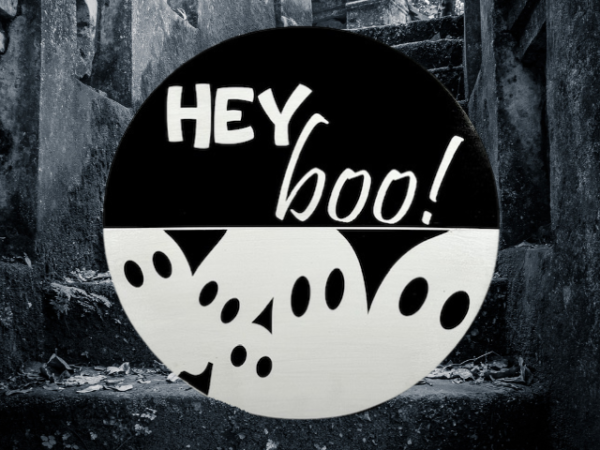 black and white pine round Halloween sign that has ghosts at the bottom and reads Hey Boo! on the top