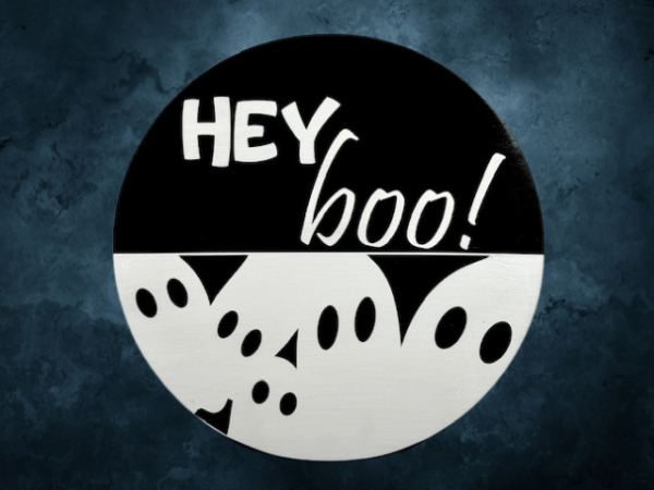 black and white pine round Halloween sign that has ghosts at the bottom and reads Hey Boo! on the top