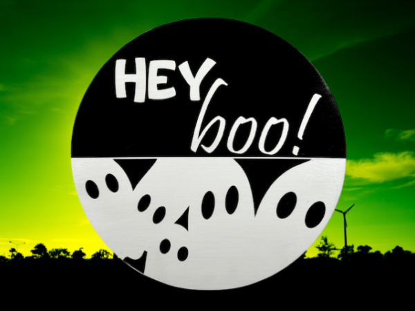 black and white pine round Halloween sign that has ghosts at the bottom and reads Hey Boo! on the top