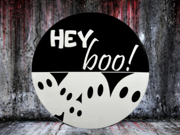 black and white pine round Halloween sign that has ghosts at the bottom and reads Hey Boo! on the top