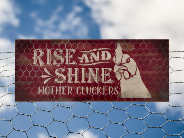 distressed and rustic red background sign with silver chicken wire - signs reads Rise and Shine Mother Cluckers