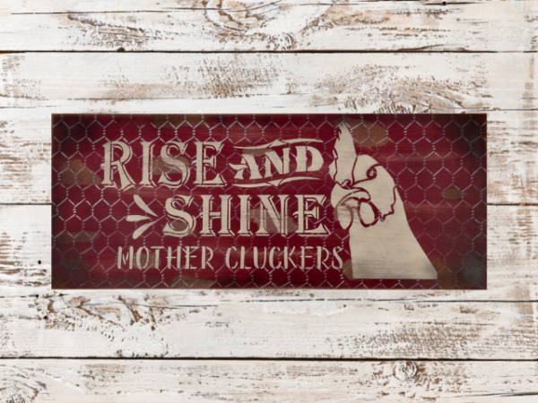 distressed and rustic red background sign with silver chicken wire - signs reads Rise and Shine Mother Cluckers