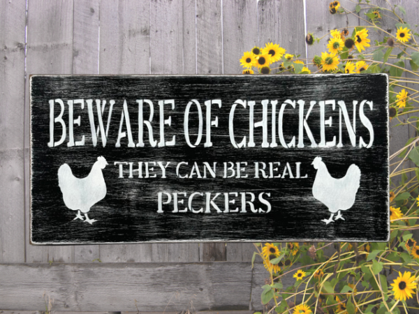 black and white distressed sign that reads "beware of chickens, they can be real peckers"