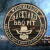 wood round pine rustic BBQ sign that reads Welcome to our Backyard BBQ - we like our meat rubbed and our pork pulled