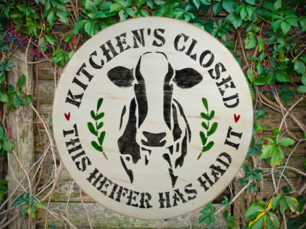 round pine wood sign that reads Kitchen's Closed - This Heifer Has Had It - with a black and white cow in the center of the round and words around the cow