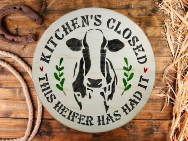 round pine wood sign that reads Kitchen's Closed - This Heifer Has Had It - with a black and white cow in the center of the round and words around the cow