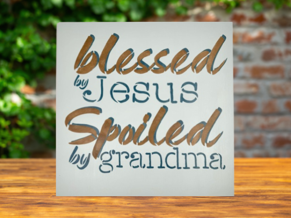 sign that reads "Blessed by Jesus Spoiled by Grandma" on a calm, pastel blue background