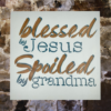 sign that reads "Blessed by Jesus Spoiled by Grandma" on a calm, pastel blue background