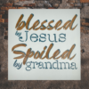 sign that reads "Blessed by Jesus Spoiled by Grandma" on a calm, pastel blue background