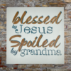 sign that reads "Blessed by Jesus Spoiled by Grandma" on a calm, pastel blue background
