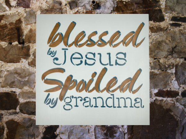 sign that reads "Blessed by Jesus Spoiled by Grandma" on a calm, pastel blue background