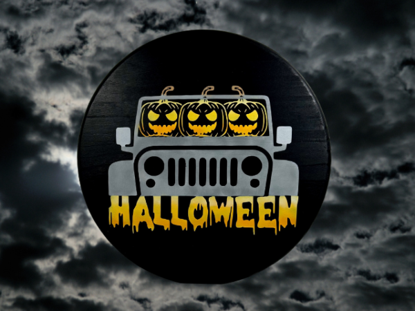 Round pine Halloween sign that has a rich black background and three pumpkin heads driving a gray Jeep - the word Halloween is written below in orange, yellow, and white ombre hues