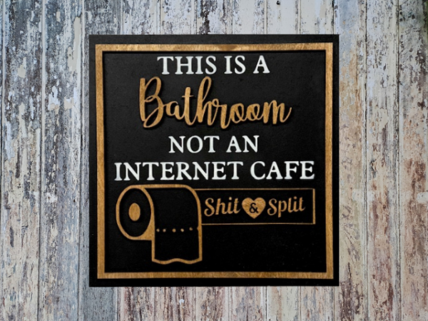 humorous laser-cut bathroom sign on a black background and stained laser lettering
