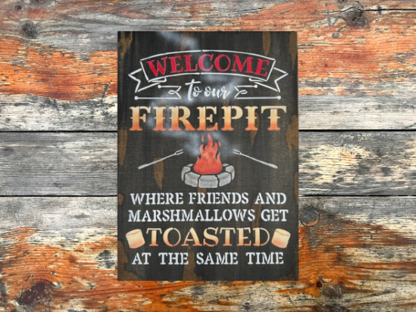 rustic campfire sign that reads "Welcome to our Firepit in beautiful orange and yellow ombre letters - the phrase "where friends and marshmallows get toasted at the same time" are painted at the bottom