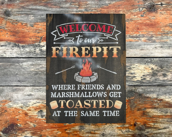 rustic campfire sign that reads "Welcome to our Firepit in beautiful orange and yellow ombre letters - the phrase "where friends and marshmallows get toasted at the same time" are painted at the bottom