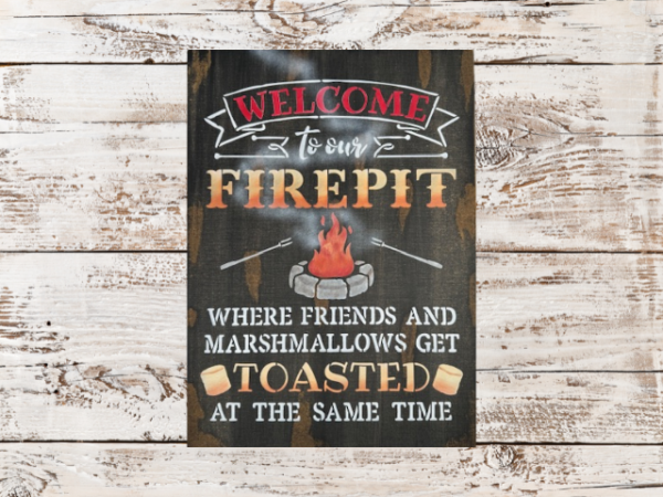 rustic campfire sign that reads "Welcome to our Firepit in beautiful orange and yellow ombre letters - the phrase "where friends and marshmallows get toasted at the same time" are painted at the bottom