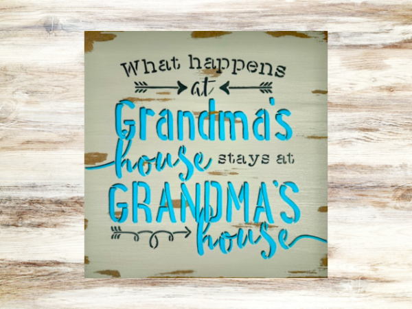 grandma's sign with a distressed mushroom gray background that says "what happens at grandma's house stays at grandma's house in teal lettering outlined in dark gray