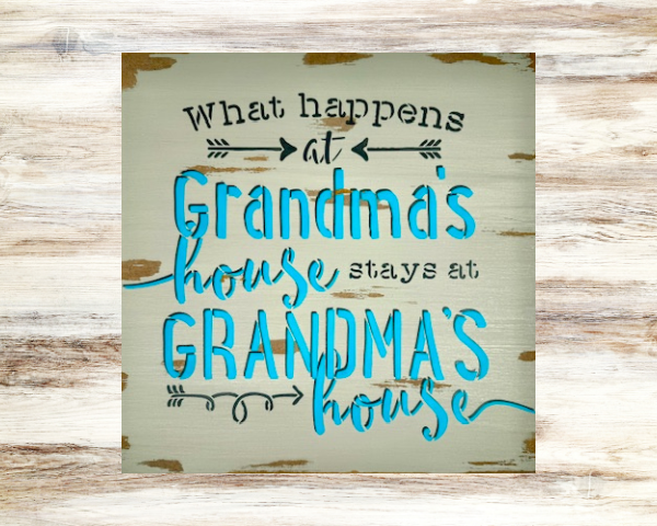 grandma's sign with a distressed mushroom gray background that says "what happens at grandma's house stays at grandma's house in teal lettering outlined in dark gray