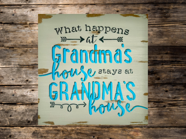 grandma's sign with a distressed mushroom gray background that says "what happens at grandma's house stays at grandma's house in teal lettering outlined in dark gray